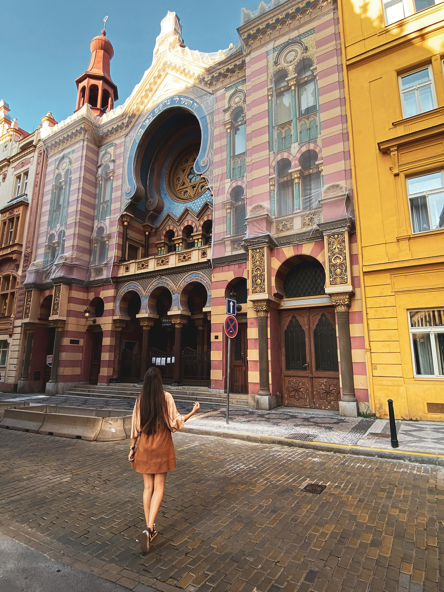 Woman walking towards a rose synagogue in Prague