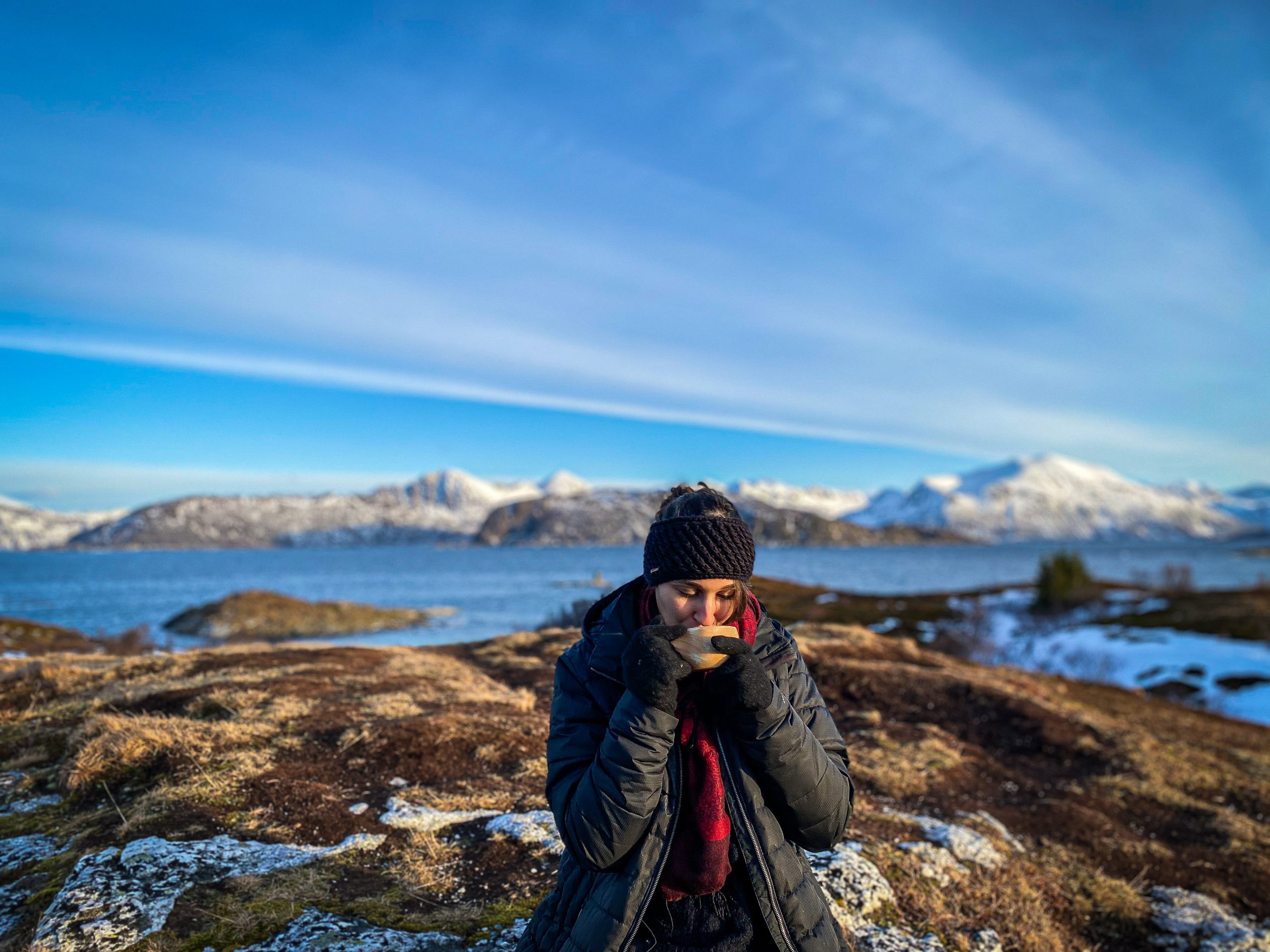 Woman drinking a hot chocolate in a fjord in Norway near Tromsø