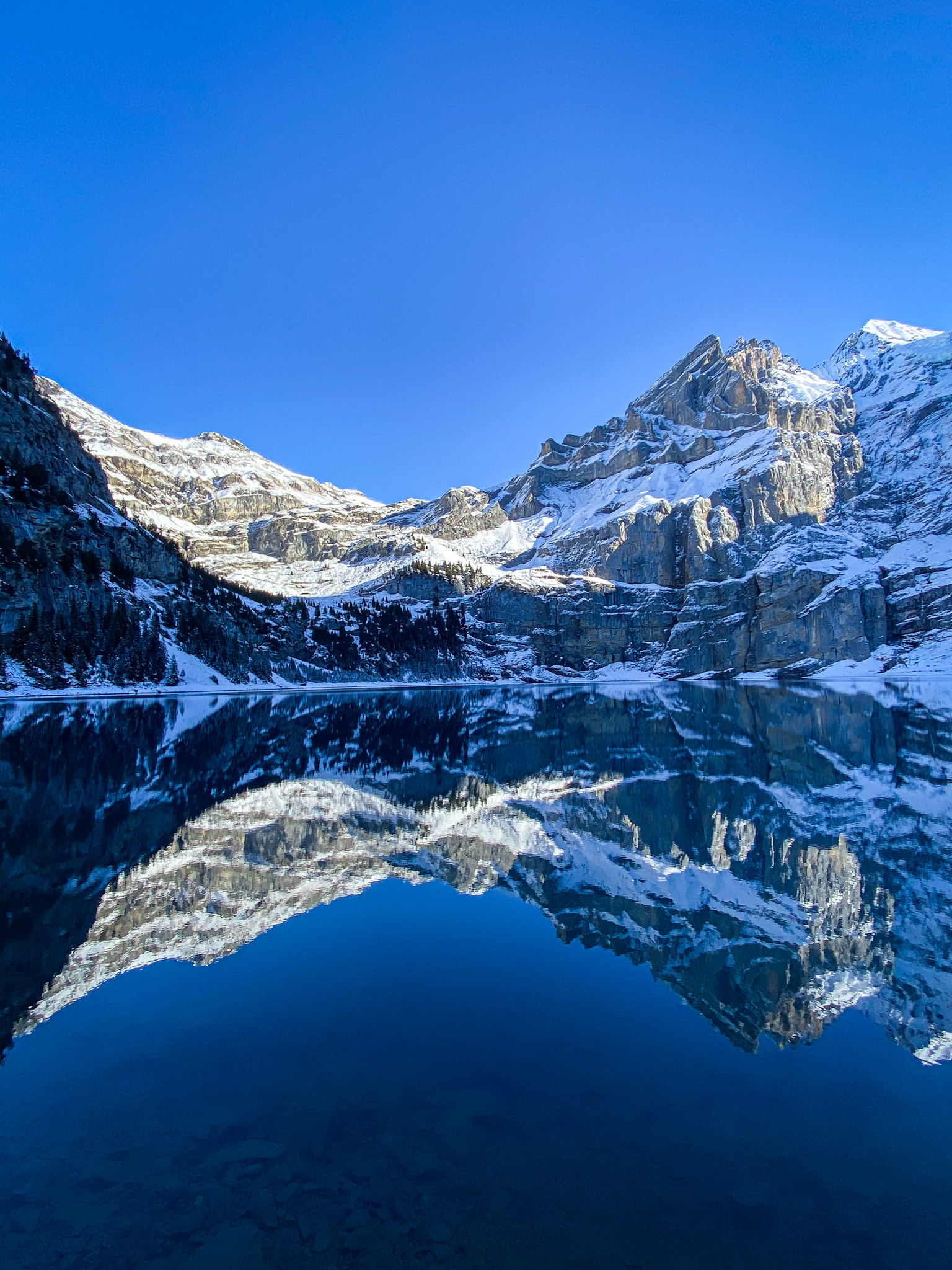 Oeschinensee in winter with snowy mountains reflected in the lake