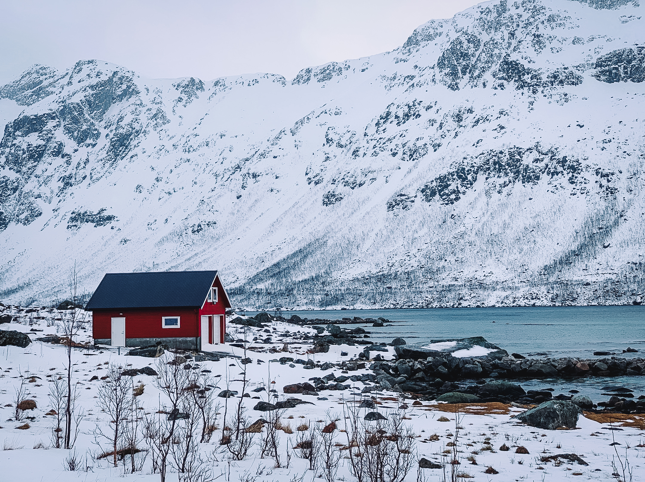 Typical red house in a snowy fjord in Norway near Tromsø