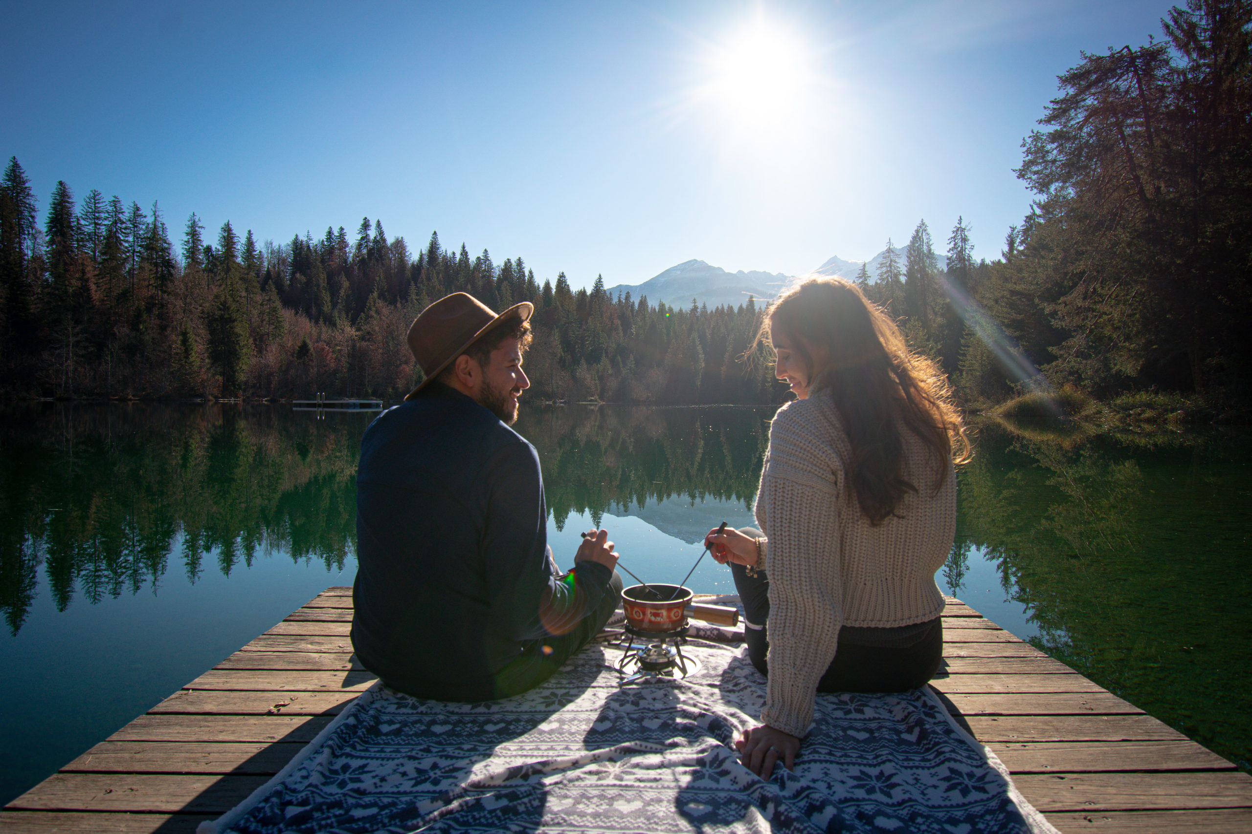 Two people eating a fondue on a deck on a lake in Switzerland