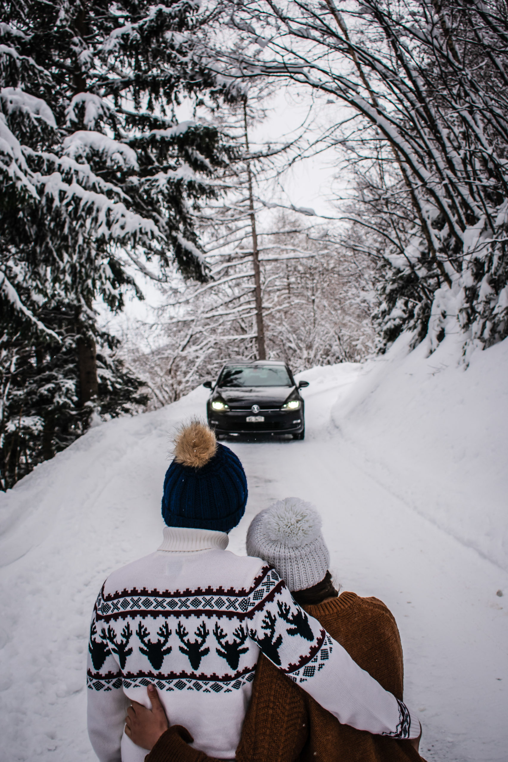 two people in the snow standing in front of a car VW Golf